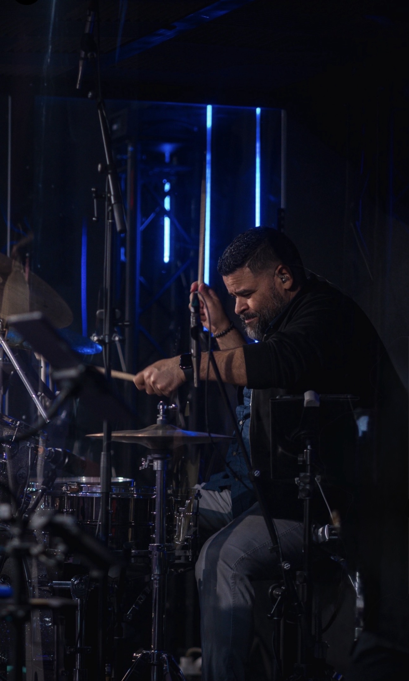 Emanuel Lozada performing live behind the drum kit under blue stage lights