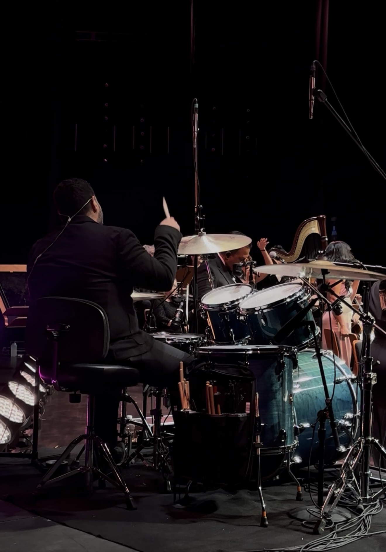 Emanuel Lozada performing live on drums under purple stage lights